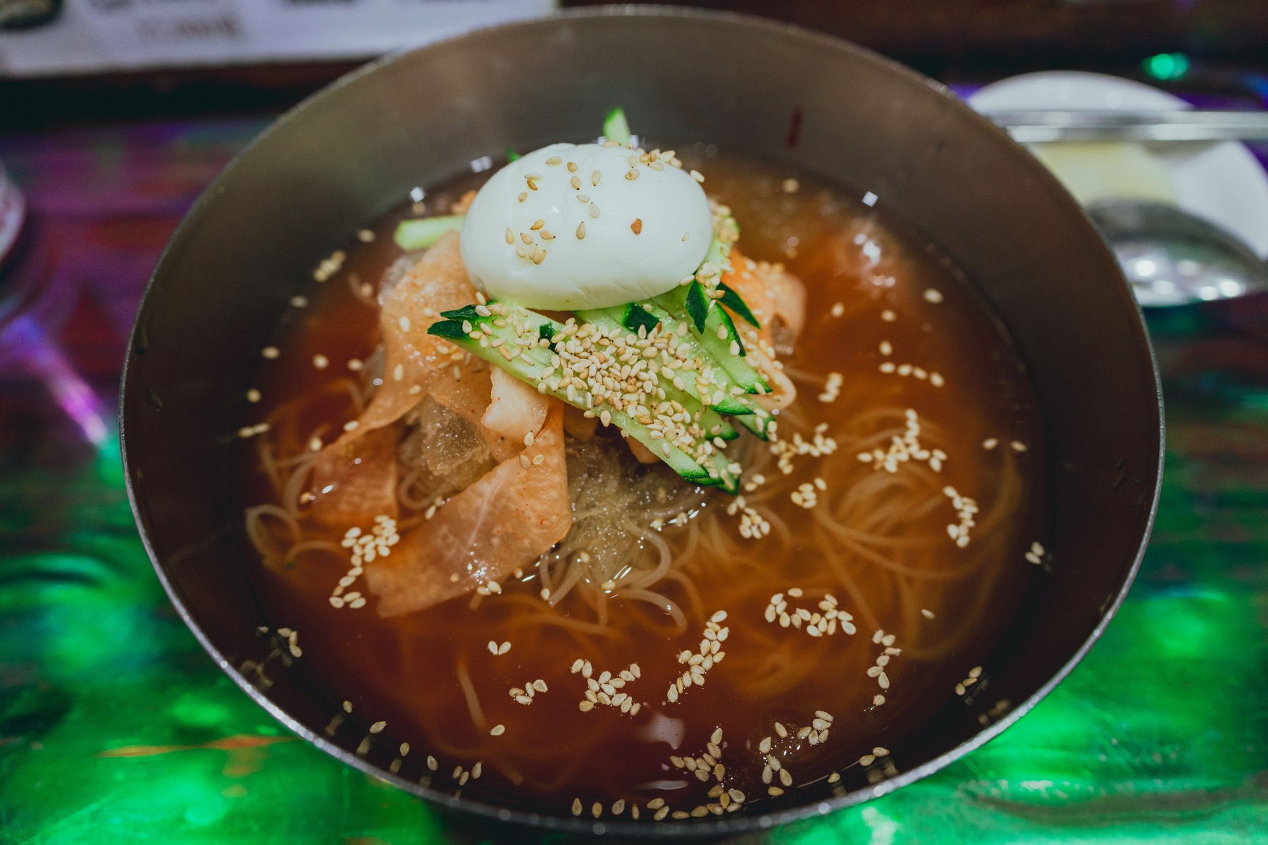 Cold Korean noodles topped with egg, cucumber and sesame