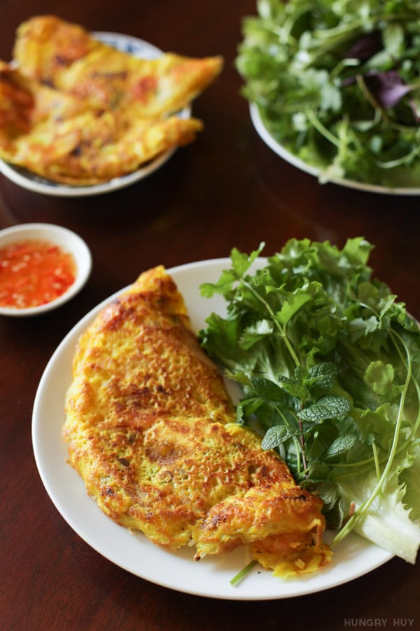 Những chiếc bánh xèo vàng giòn ăn kèm rau sống và rau thơm.