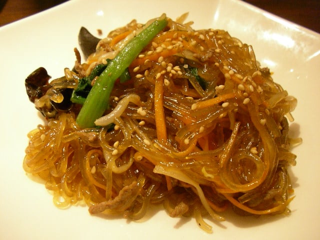 Glossy Korean japchae glass noodles with colourful vegetables.