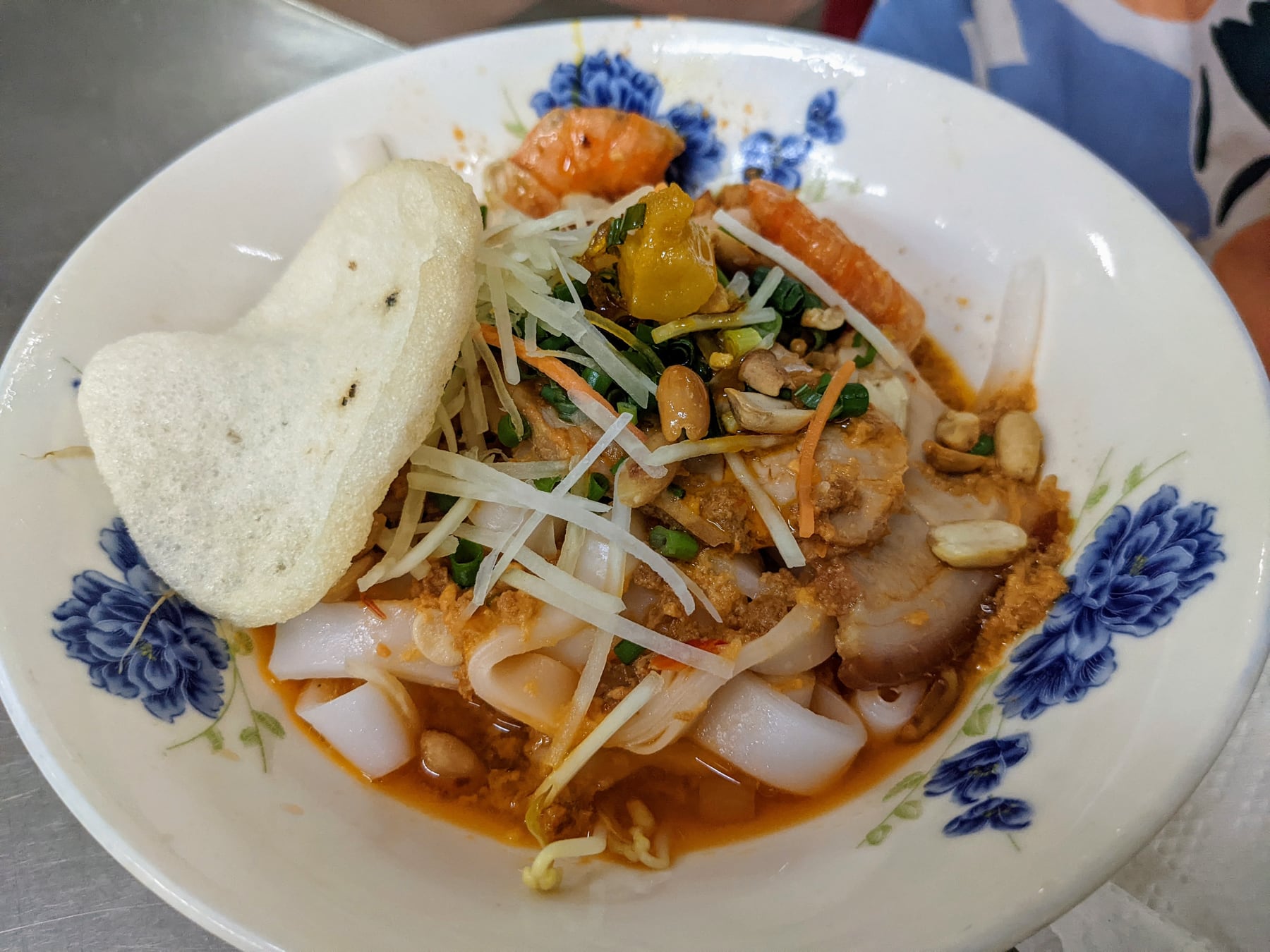 Tô mì Quảng vàng với gà, tôm, rau thơm, đậu phộng và bánh tráng.