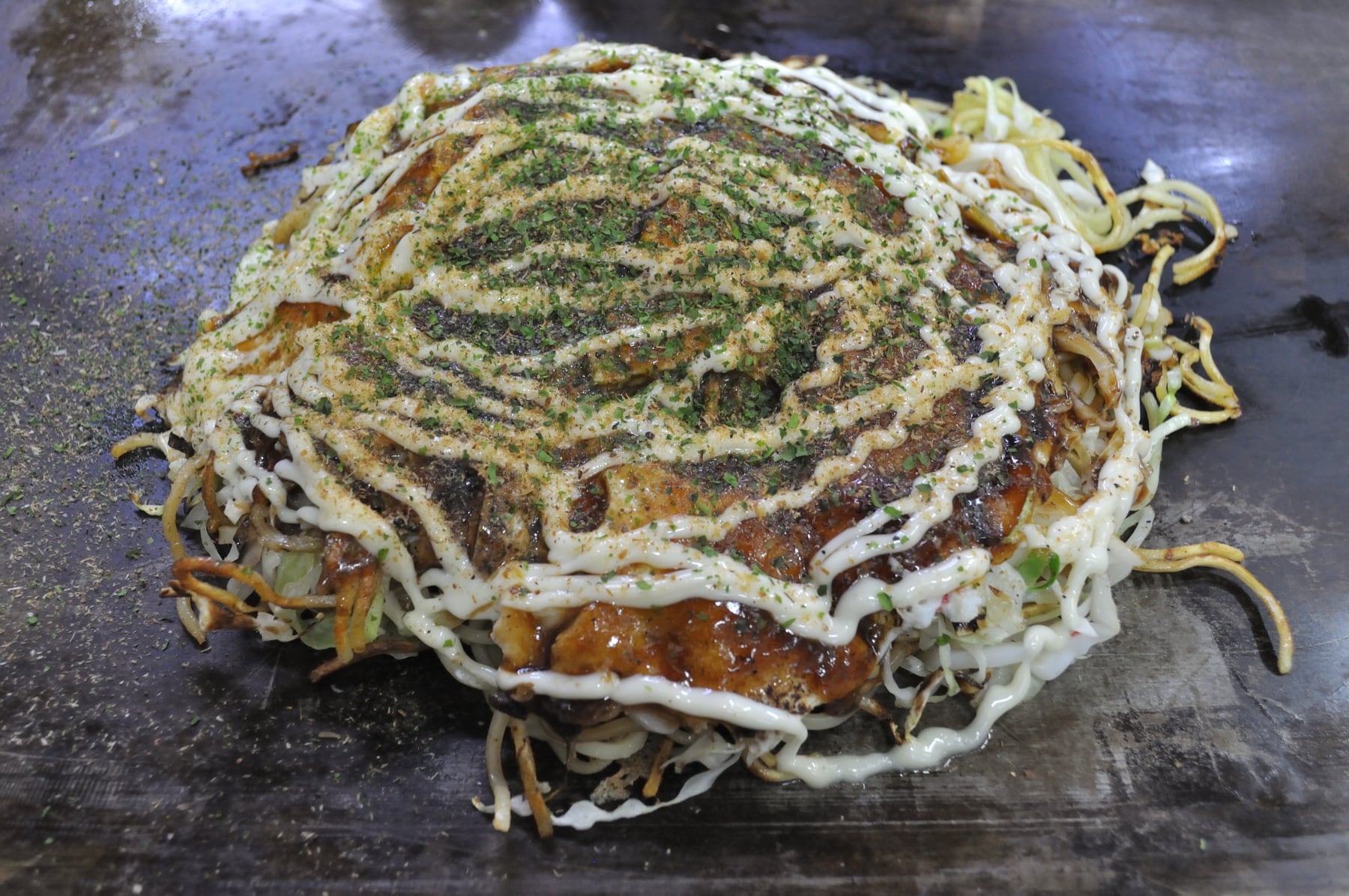 Japanese okonomiyaki cabbage pancake topped with sauce and mayonnaise.