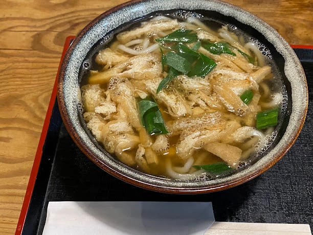 Súp udon Nhật với sợi mì dày, đậu phụ và hành lá.