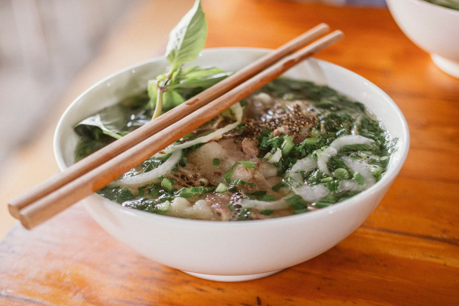 Schüssel vietnamesische Phở mit Rindfleisch, Reisnudeln und frischen Kräutern