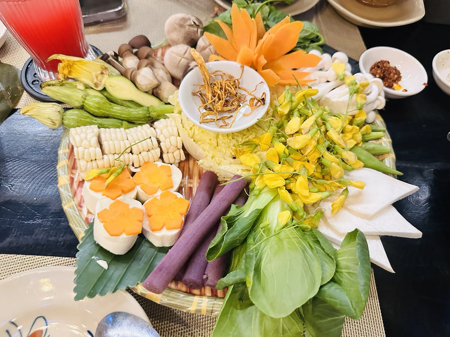 Bunte vegane Zutatenplatte mit Gemüse, Pilzen, Mais, Tofu und Blüten
