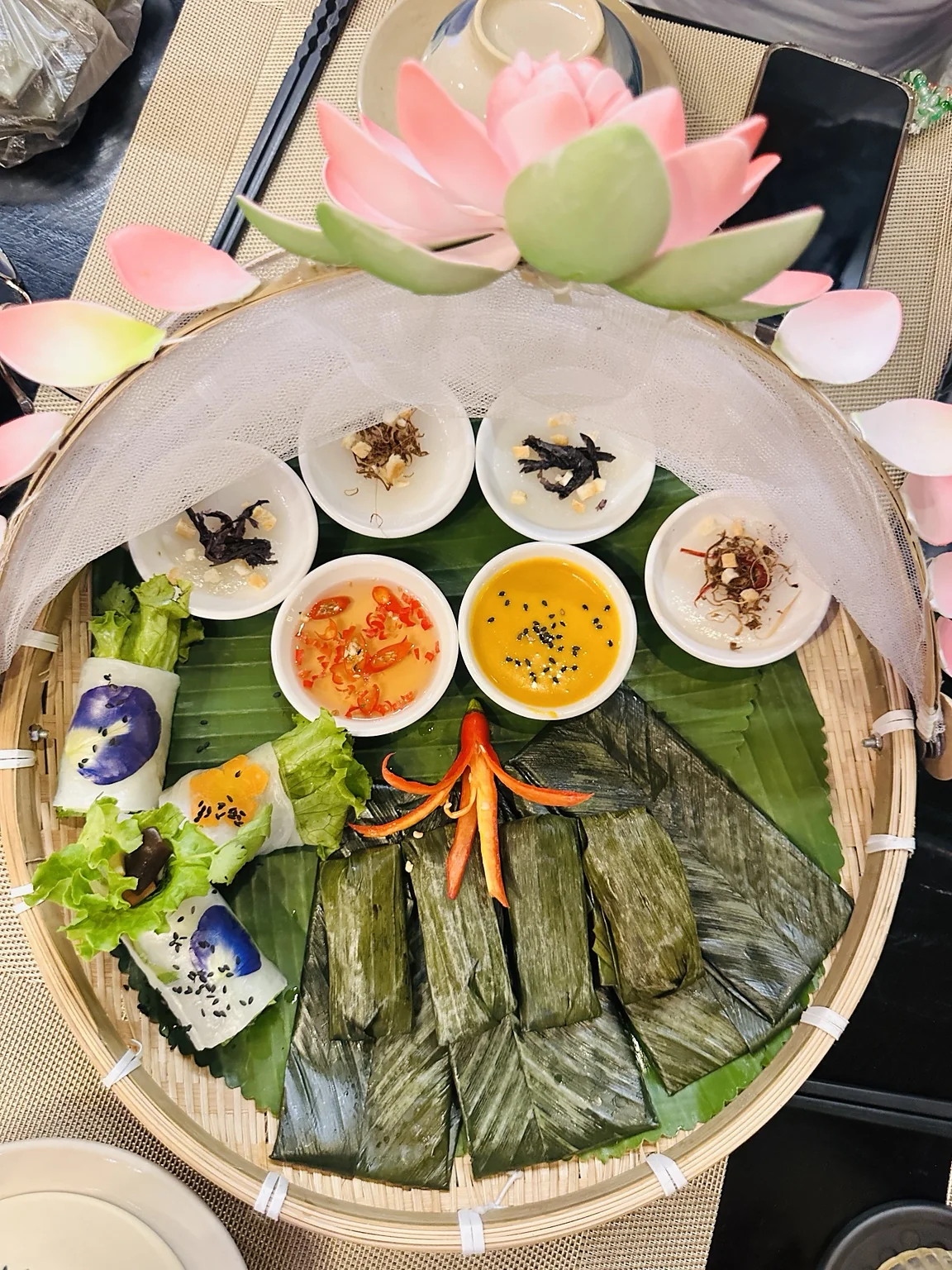 Vegane vietnamesische Vorspeisen und in Blätter gewickelte Spezialitäten auf einem Bambustablett